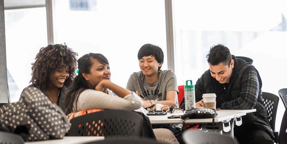 four nutrition students laughing and smiling together while sitting at table